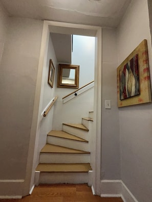 Eine Treppe mit Holzsitzstufen, weißen Wänden und einem Gemälde an der Wand.