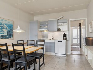 A modern kitchen with a dining area, white cabinetry, and a painting on the wall. - 5 Star Holiday Home in Glesborg (Glesborg)