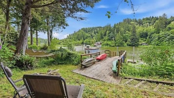 A wooden dock extending into a lake, surrounded by lush greenery and trees.