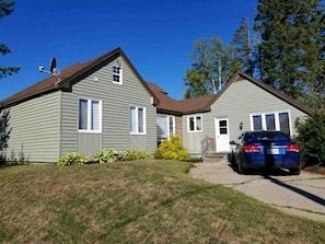 A two-story house with a satellite dish, a car parked in the driveway, and a well-maintained lawn.