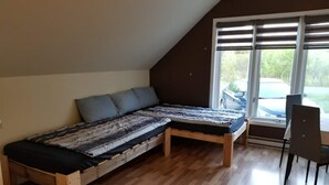 Quarto estilo loft com piso de madeira, uma cama com colcha estampada, uma janela com persianas e uma cadeira.