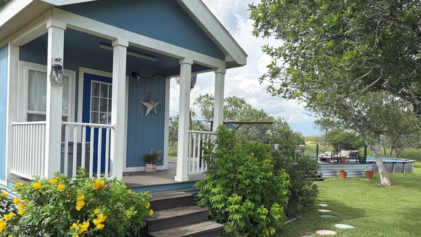A house with a porch, steps leading to the entrance, and a garden with stepping stones.