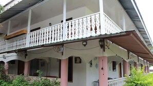 A two-story building with a balcony, a tiled floor, and a porch area.