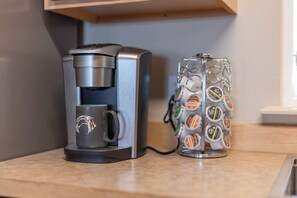 Eine Kaffeemaschine und eine Tasse mit Kaffeekapseln auf einer Arbeitsplatte.