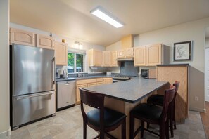 A modern kitchen with a central island, stainless steel appliances, and wooden cabinetry. - Warm & Friendly Condo Downtown Coeur d'Alene (Coeur d'Alene)