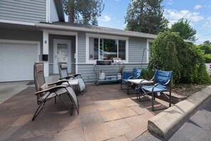 A residential garage with a white door, a number '8' sign, and a patio area with outdoor furniture and a grill. - Warm & Friendly Condo Downtown Coeur d'Alene (Coeur d'Alene)