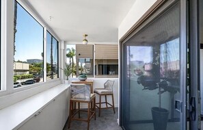 A balcony with two wicker chairs, a small table, and a potted plant. - Peaceful 2-Bedroom Condo in Sunny La Jolla (San Diego)