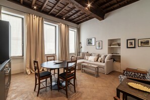 Ein Wohnzimmer mit Esstisch, Sofa und Fernseher.