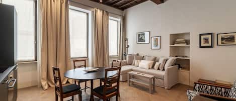 A living room with a dining table, sofa, and a television.