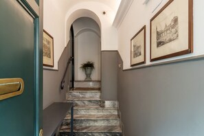 Ein Flur mit einer Marmortreppe, einer Zimmerpflanze und gerahmten Bildern an den Wänden.
