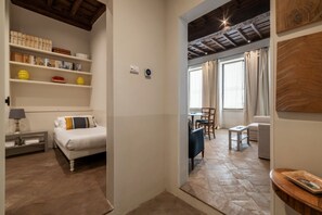 A bedroom with a bed, bedside table, lamp, and shelves with books and decorative items. - Coronari 6 - FromHometoRome (Roma)