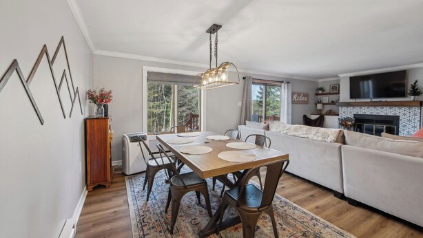 Una sala de estar moderna con comedor, chimenea y televisor montado en la pared.