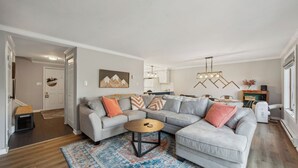 Una sala de estar moderna con un sofá modular, una mesa de centro redonda y un comedor al fondo.