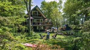 Eine zweistöckige Holzhütte mit Balkon, umgeben von dichtem Wald.