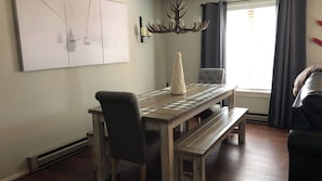 Ein Essbereich mit Holztisch, Stühlen, einer Bank, einer Chandelüster und einer Wandleuchte.