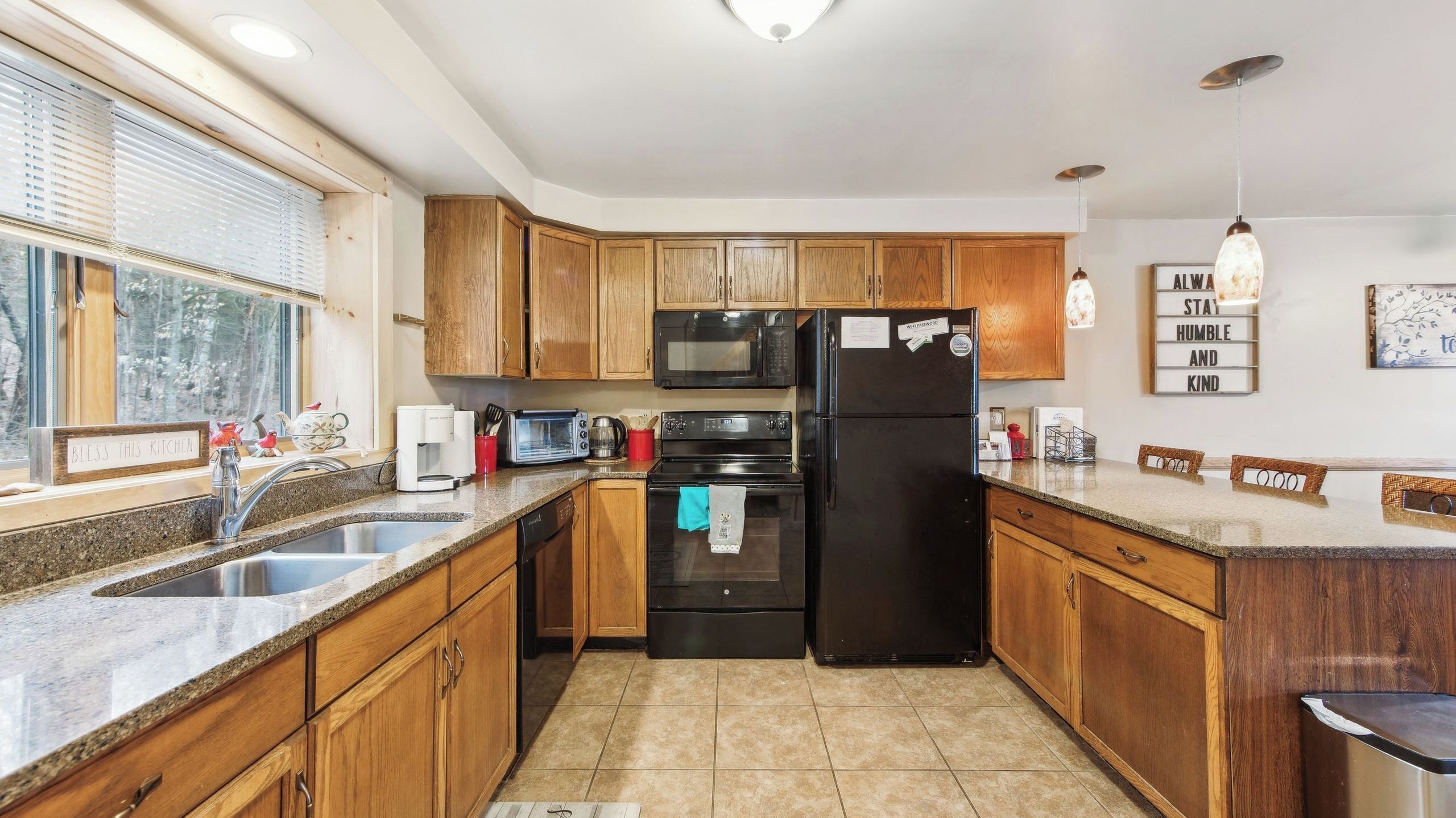 A kitchen with wooden cabinets, a black refrigerator, a microwave, a toaster, and a coffee maker.