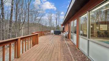 A wooden deck with outdoor seating and a barbecue grill.