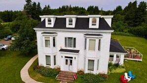A two-story white house with a front porch, a covered deck, and a driveway. - New Glasgow Inn (New Glasgow)