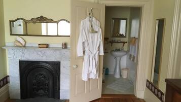 A room with a fireplace, a mirror, a sink, and a door leading to another room.
