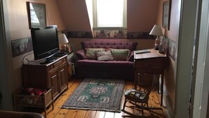 A small room with a television, a sofa, a rocking chair, and a window with blinds. - New Glasgow Inn (New Glasgow)
