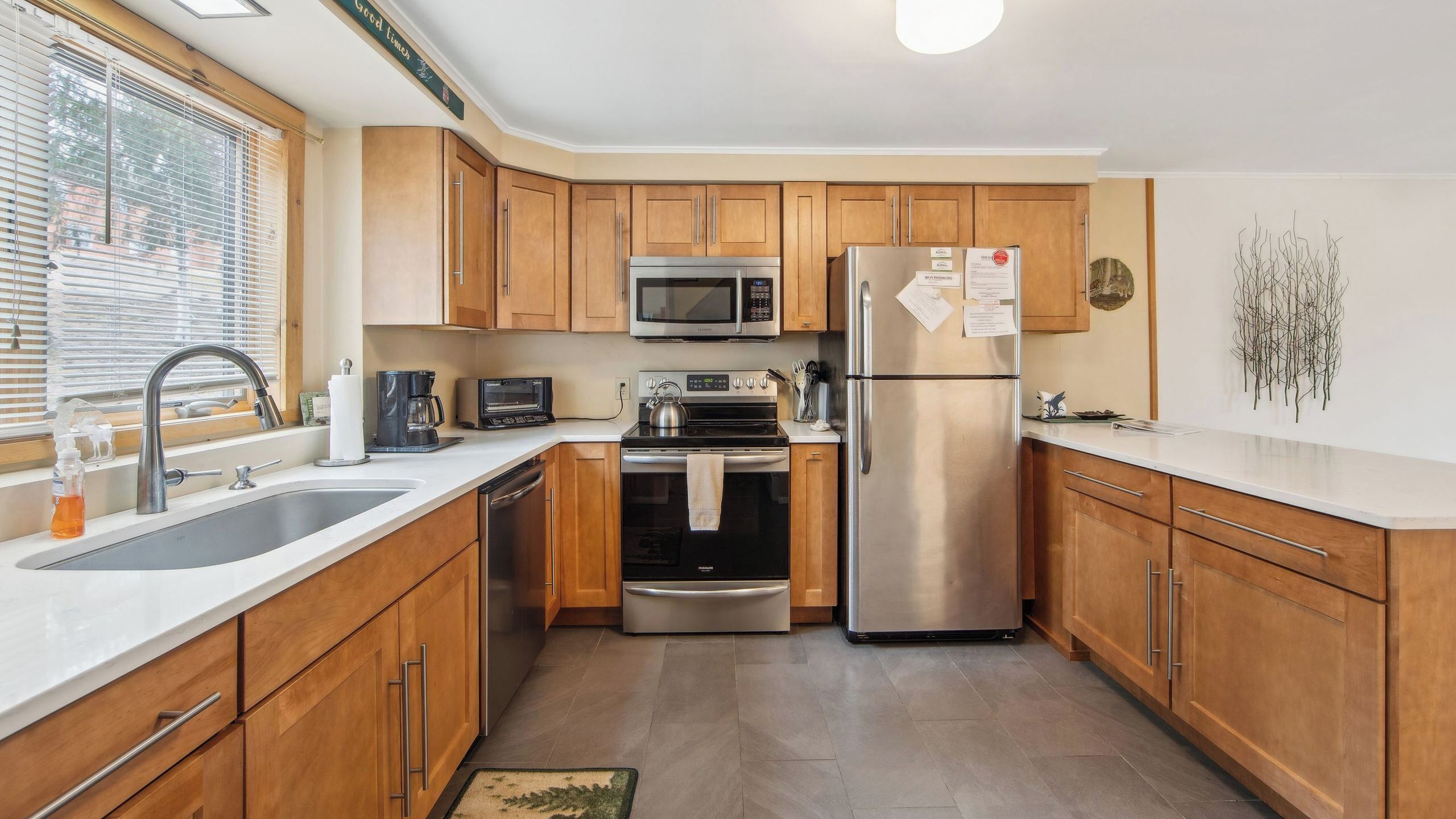 A modern kitchen with wooden cabinets, stainless steel appliances, a microwave, oven, and refrigerator.