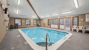 Une piscine intérieure dotée d’espaces dégagés autour du bassin, d’équipements de sécurité et de panneaux d’indication des sorties.