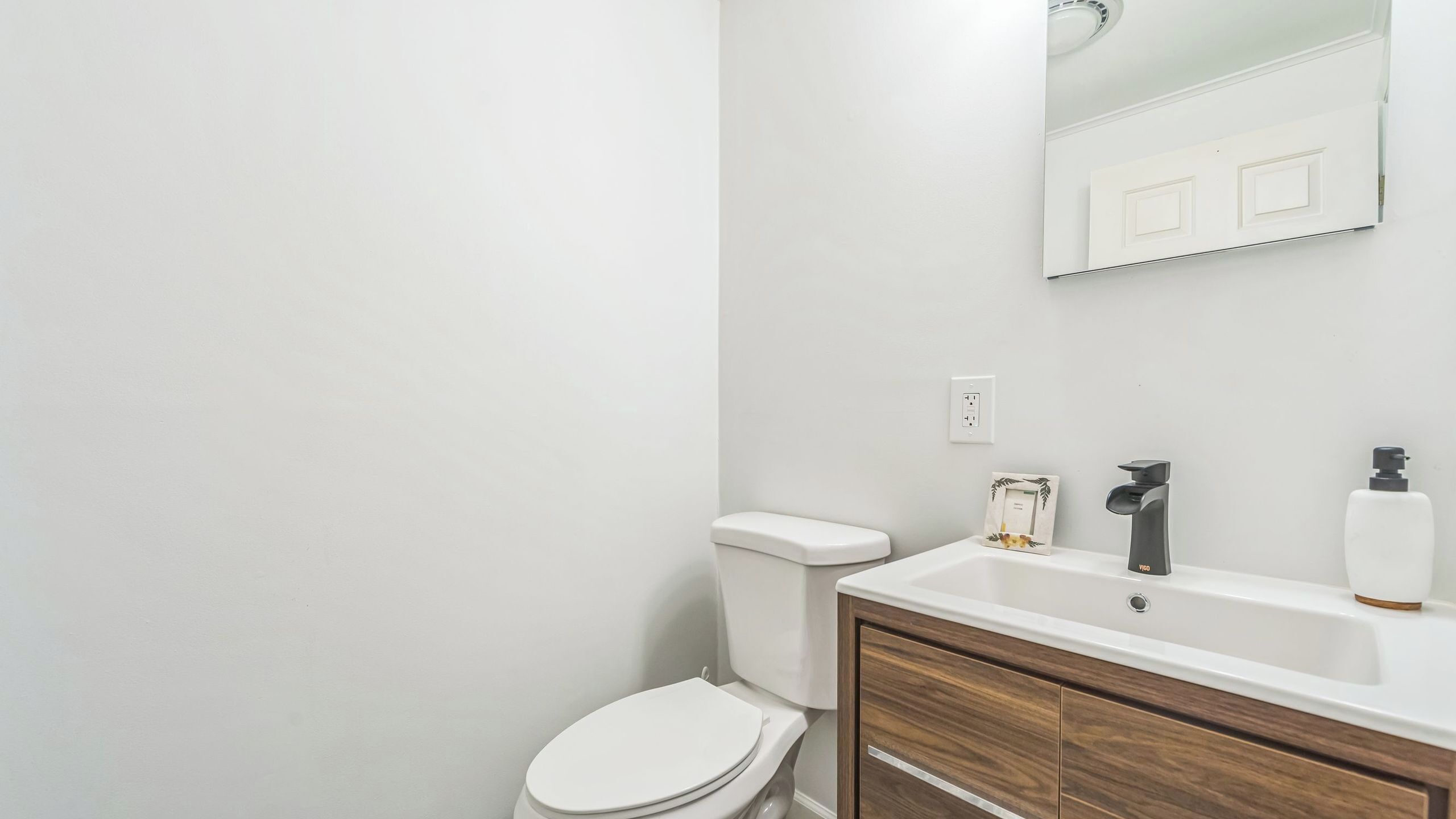 Un baño con inodoro, lavamanos y espejo.