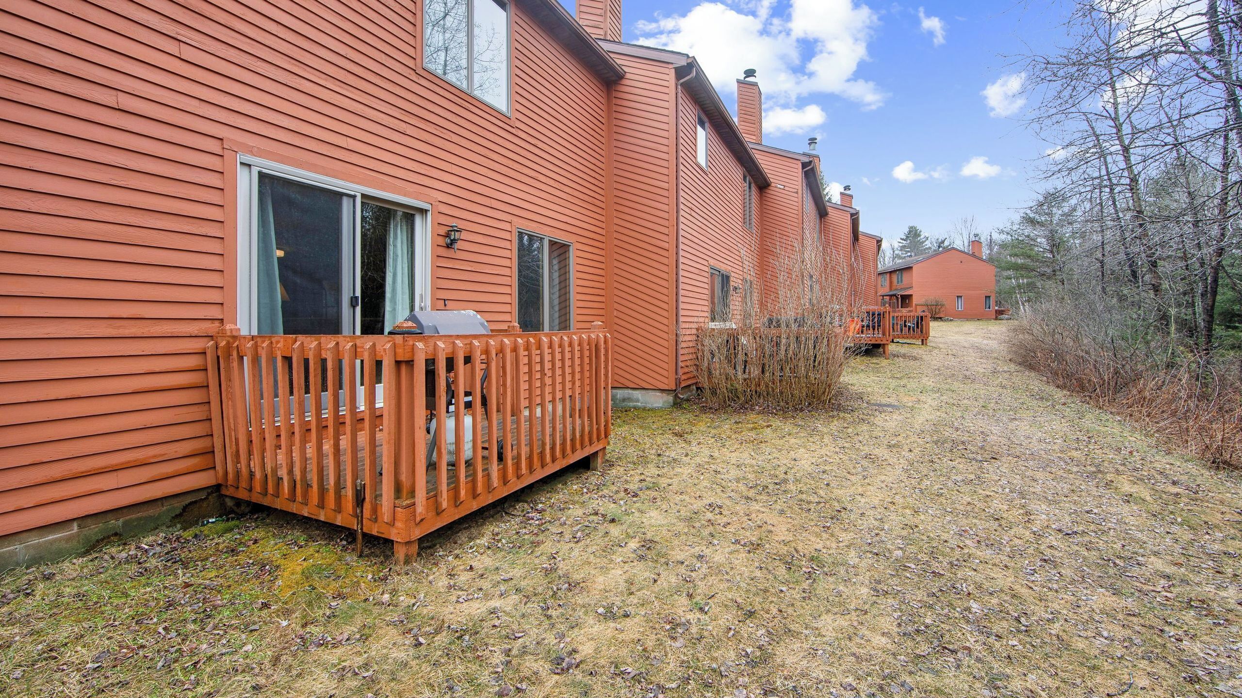 A row of red wooden buildings with a wooden deck and a gravel path.