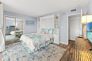Ein Schlafzimmer mit Bett, einem großen Spiegel, einem Fernseher und einem Kleiderschrank.
