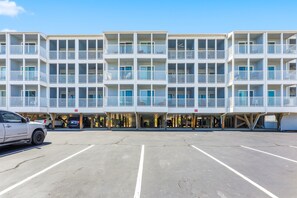 Ein mehrstöckiges Hotel mit Balkonen, einem Parkplatz und blauem Himmel.