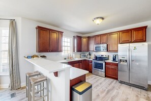 A modern kitchen with wooden cabinets, stainless steel appliances, and a white countertop. - Stellar Lakefront Oasis With Kayaks, Sup, Firepits, Dock, & Games - Dog-friendly (Mineral)
