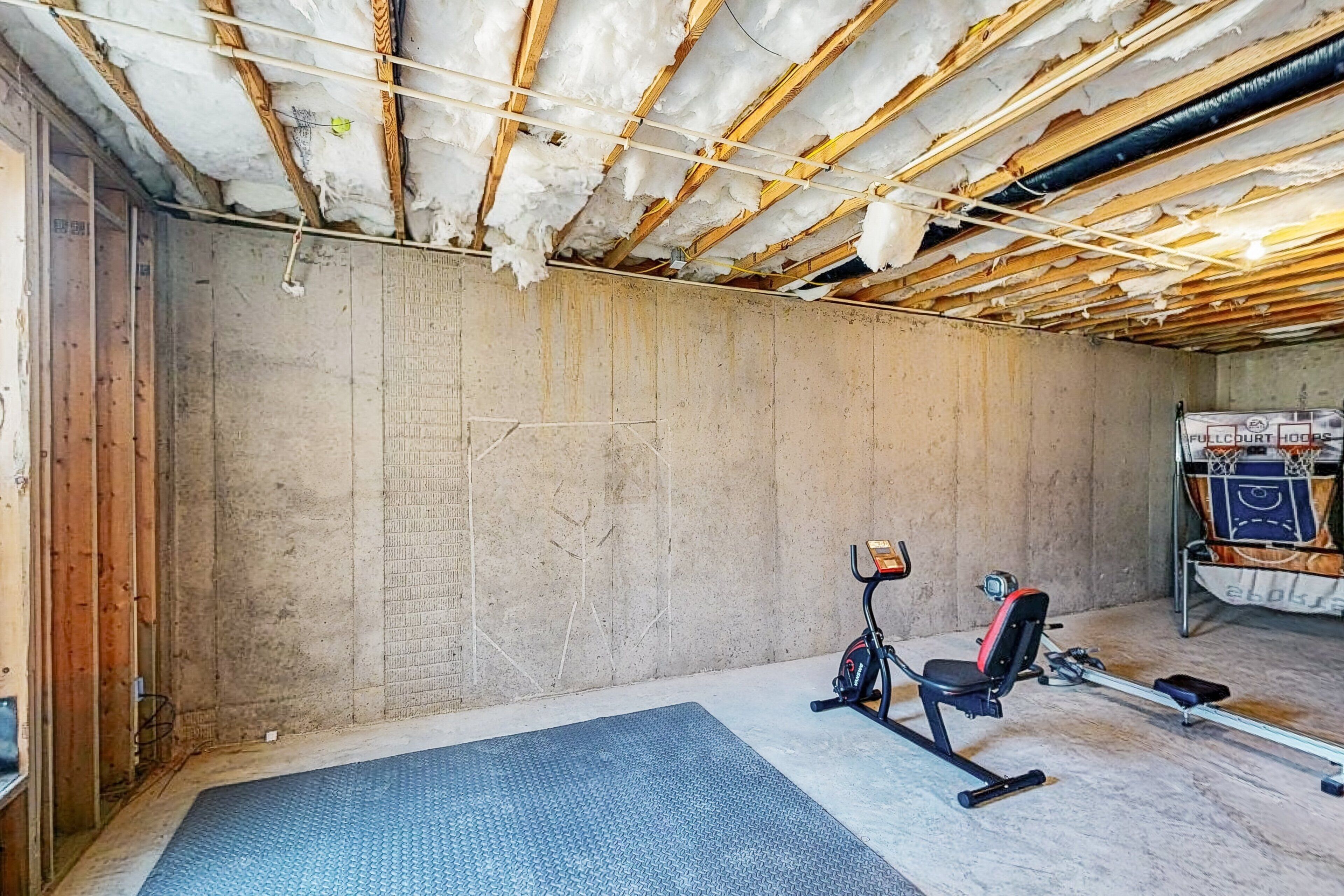 A room with a concrete wall, a blue exercise mat, and an exercise bike.