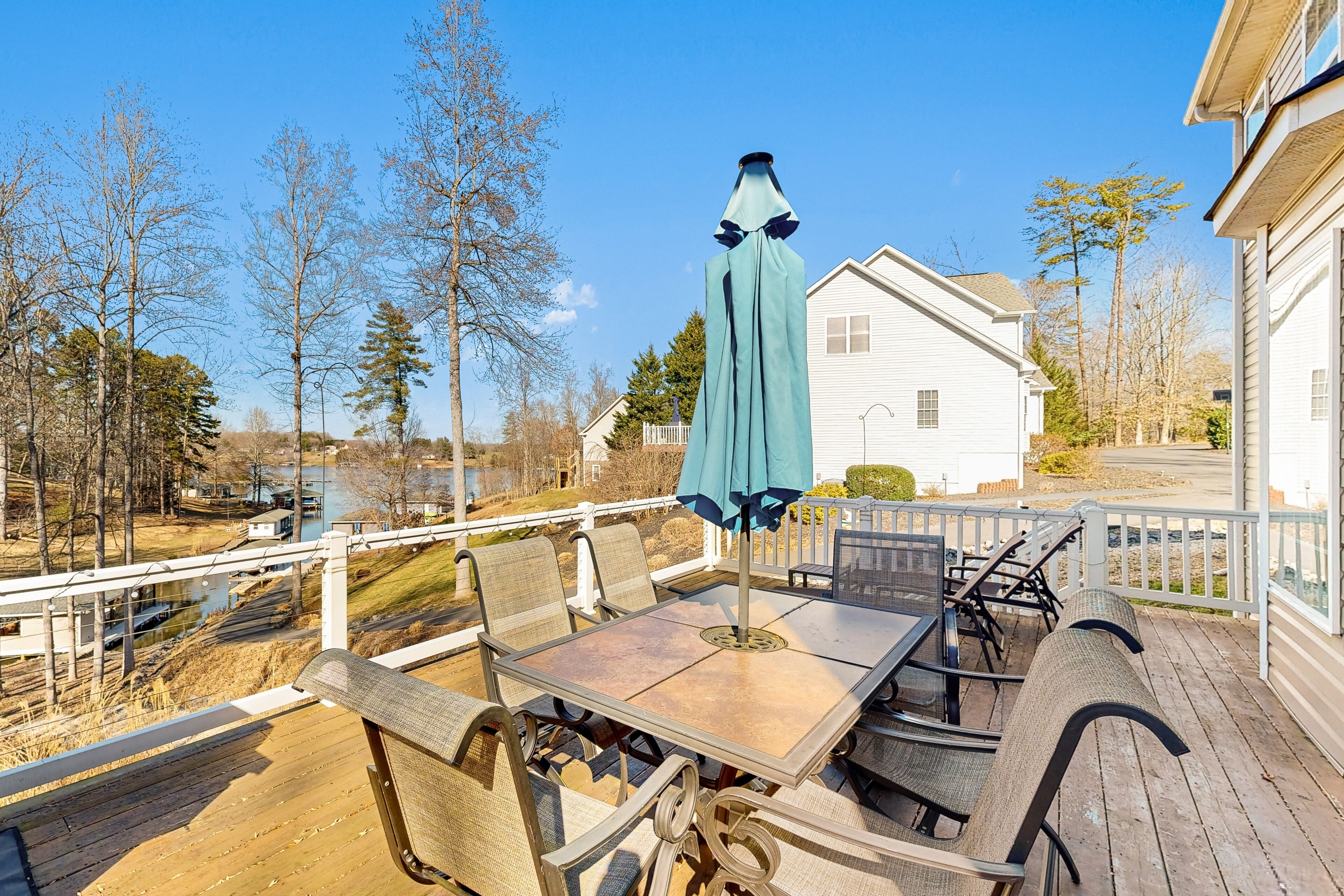 Eine Terrasse mit Tisch und Stühlen mit Blick auf einen Fluss und ein weißes Haus.