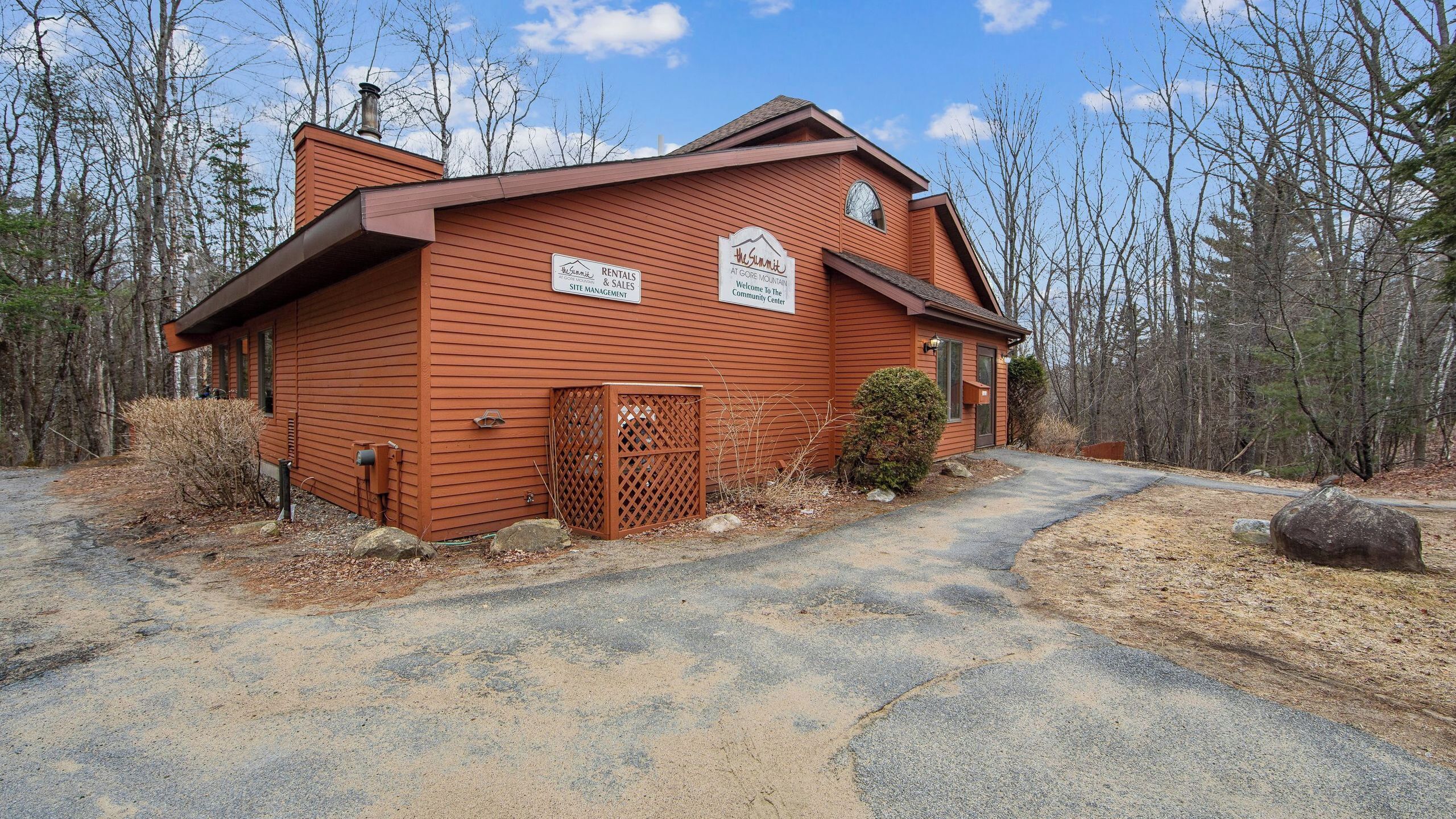A wooden building with signs for rentals, sales, and a community center.