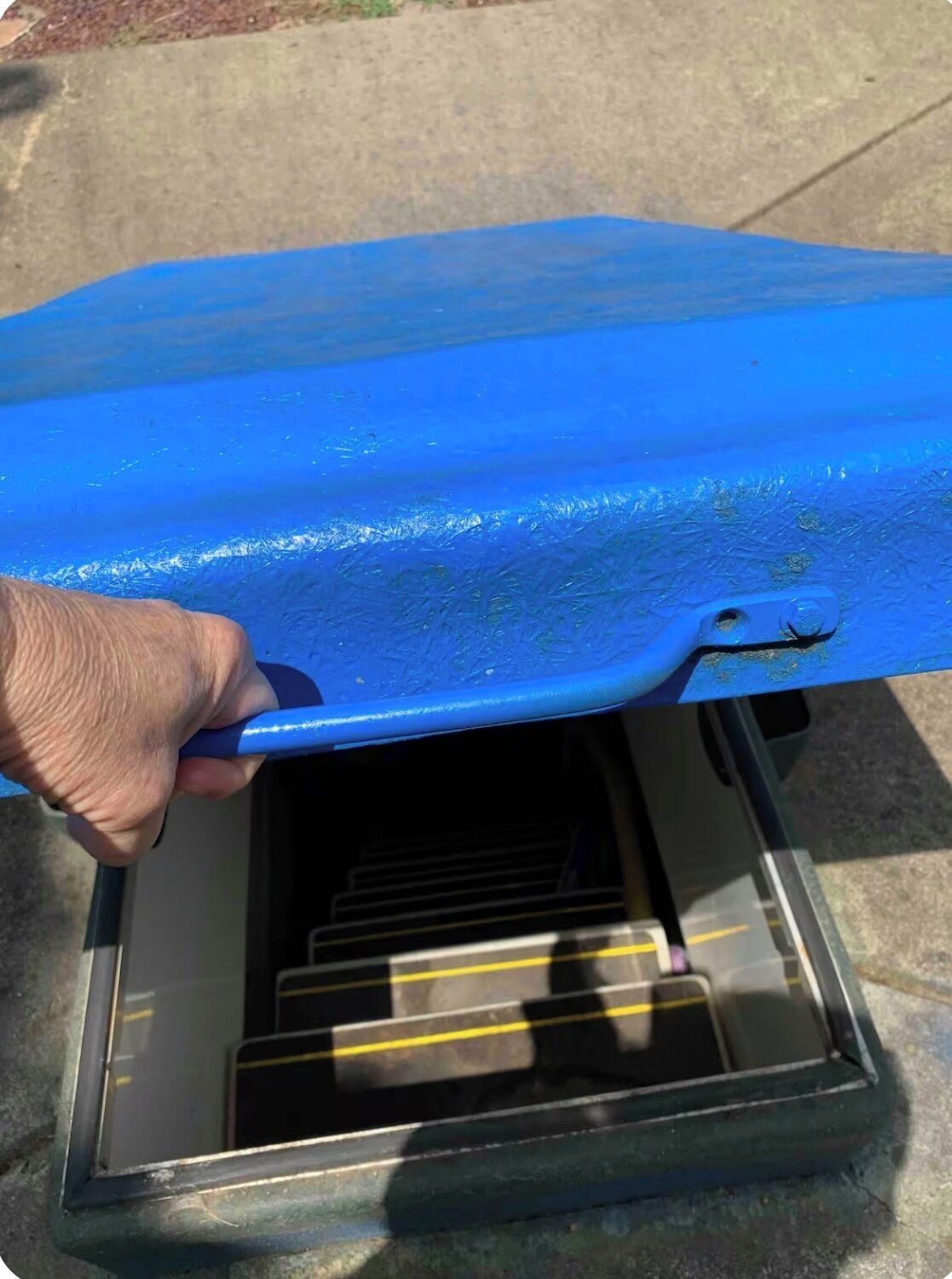 A hand holding a blue object over a transparent container with yellow lines.