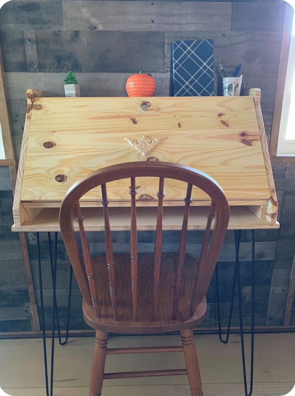 Un tavolo in legno con un pannello decorativo, una piccola pianta in vaso e una zucca sopra il tavolo.