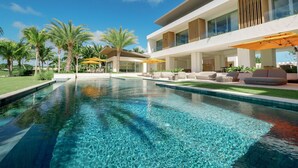 A modern pool area with clear water, outdoor seating, and a two-story building with large windows. - Shemesh Residence - Ocean Golf Views With Full Staff at Unique Cap Cana Villa (Punta Cana)