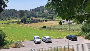 A parking lot with three cars, a grassy field, and a building in the background. - Air-conditioned village house with unobstructed view of the countryside (CALLAS)