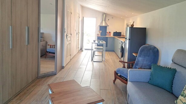A modern living room with a sofa, a wooden coffee table, and a kitchen area with a stove and refrigerator. - Air-conditioned village house with unobstructed view of the countryside (CALLAS)
