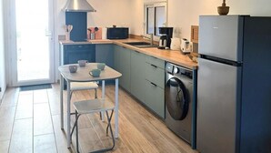 A modern kitchen with a dining area, built-in appliances, and a sliding door leading to a balcony. - Air-conditioned village house with unobstructed view of the countryside (CALLAS)