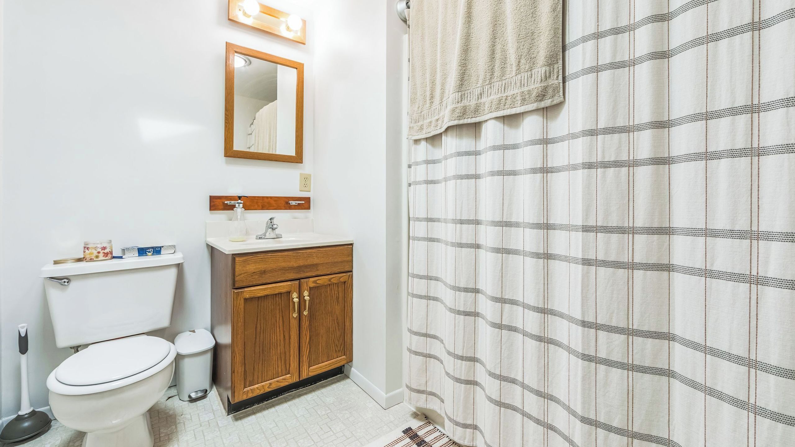 A bathroom with a toilet, sink, mirror, and striped shower curtain.