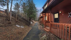 Une cabane en bois, avec un sentier menant à l’entrée, entourée d’arbres et d’une clôture en bois.