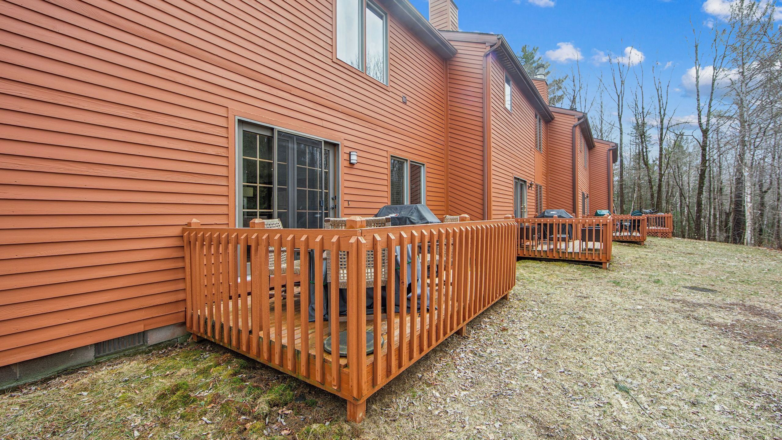 Une rangée de cabanes aux façades en bois, un patio délimité par une clôture et un ciel dégagé.