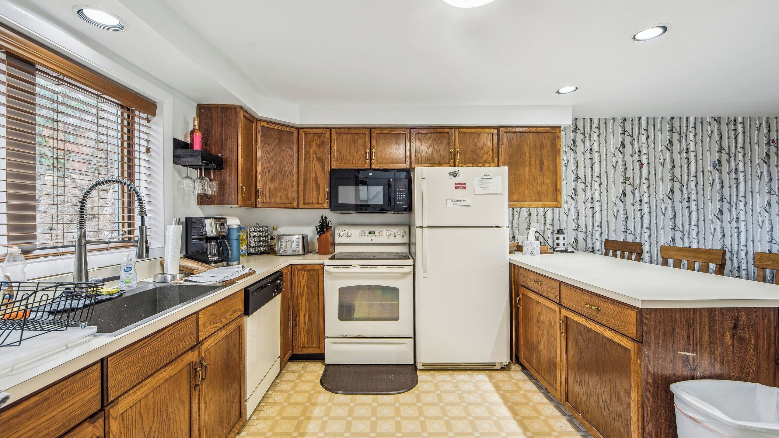 A compact kitchen with wooden cabinets, a microwave, a refrigerator, a stove, and a sink.