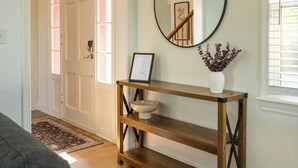 A hallway with a wooden console table, a mirror, and a vase with flowers. - Game Day Getaway - 4BR/3BA, Sleeps 10, Walk to WSU (Pullman)