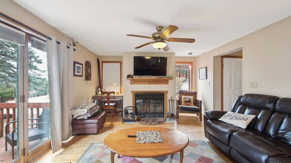 A living room with a fireplace, leather sofa, and a television. - Sagamore by Avantstay Heated Pool + Game Room Near Gore + Main St (North Creek)