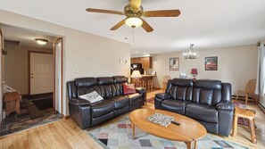 A living room with two leather sofas, a wooden coffee table, a ceiling fan, and a kitchen in the background. - Sagamore by Avantstay Heated Pool + Game Room Near Gore + Main St (North Creek)