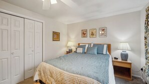 Ein Schlafzimmer mit Bett, Nachttischen, einem Kleiderschrank und Wandbildern.