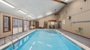 An indoor swimming pool with a ceiling fan, a water heater, and a pool ladder. - Chatiemac by Avantstay Wood Fireplace + Resort Pool + Game Room Ski Retreat (North Creek)