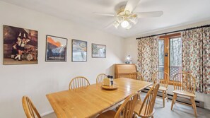 A dining area with a wooden table and chairs, a ceiling fan, and three framed posters on the wall. - Chatiemac by Avantstay Wood Fireplace + Resort Pool + Game Room Ski Retreat (North Creek)